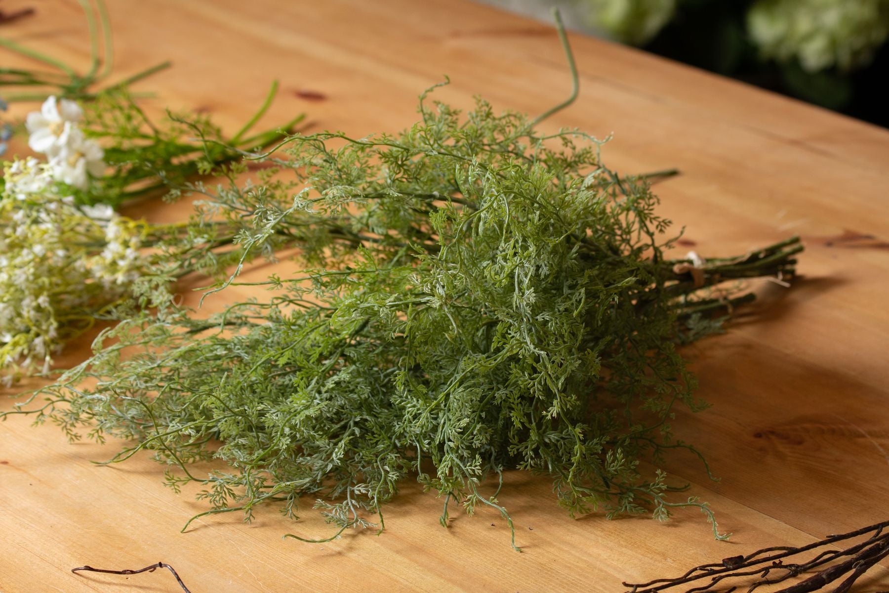 Lush green asparagus fern bunch with feathery fronds, set against a wooden surface, perfect for elegant home decor.