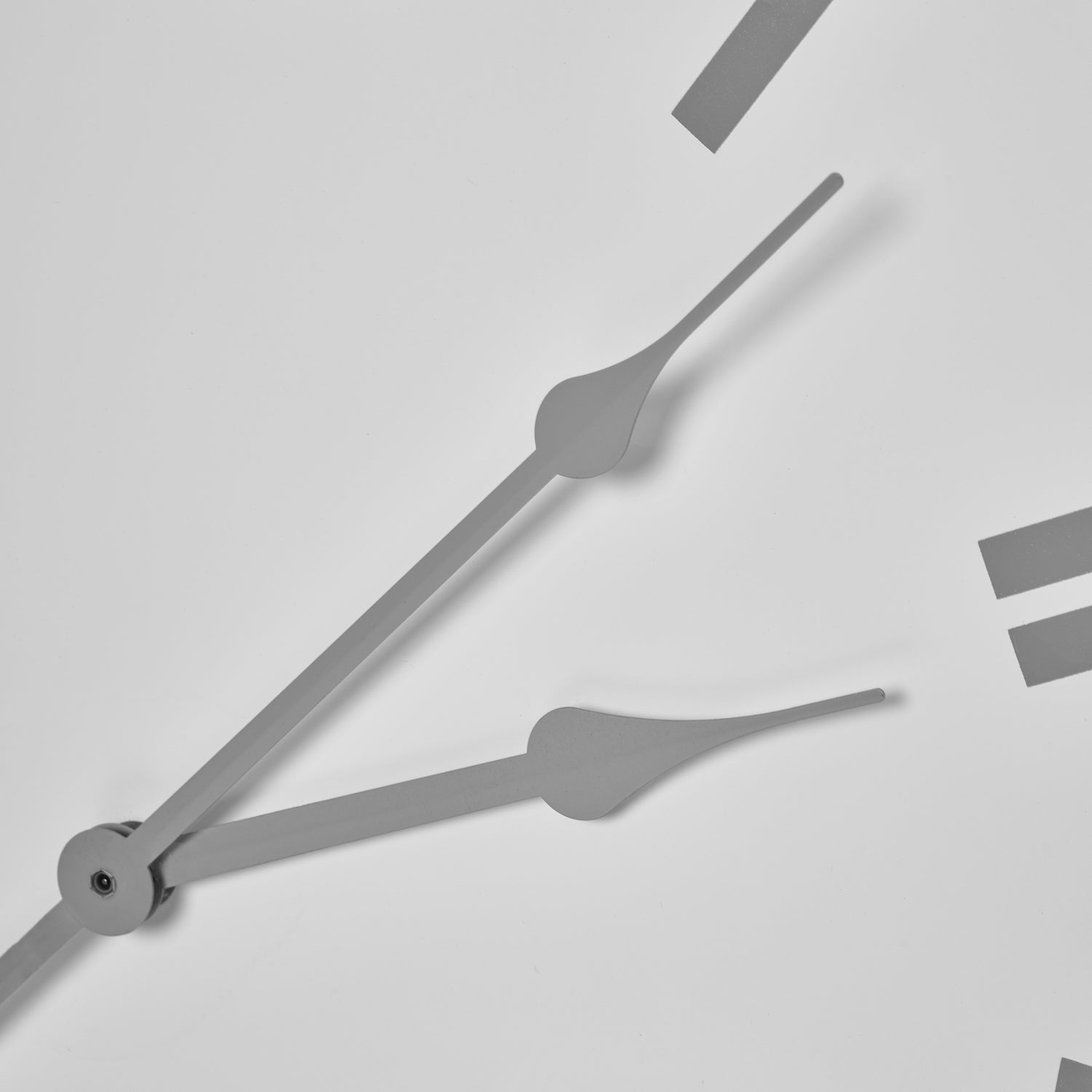 Sleek white wall clock with elegant gray hands and minimalistic markers, showcasing refined craftsmanship and modern design.