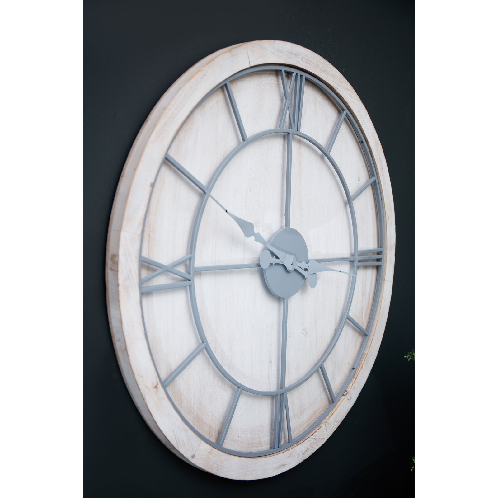 Large round wall clock with a whitewashed wood frame, light grey Roman numerals, and hands for easy readability.