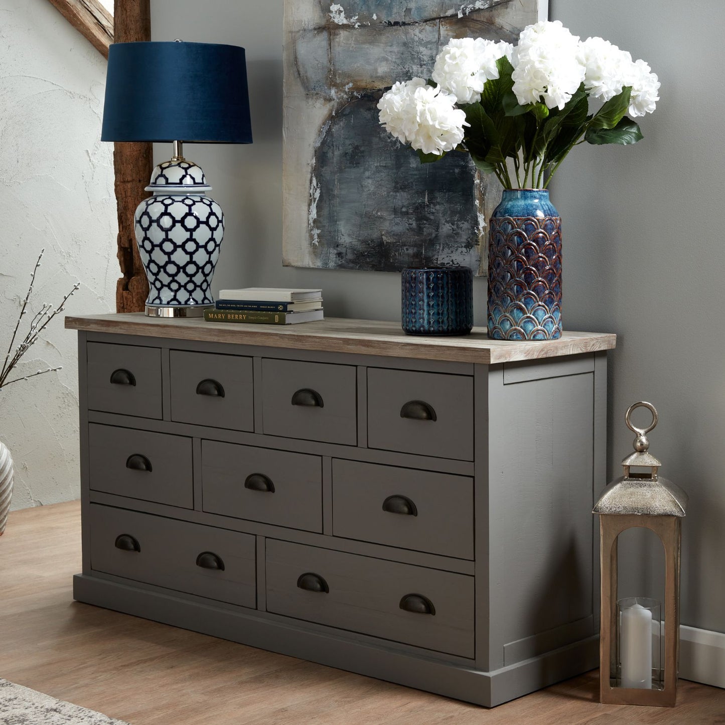 Indigo planter with a refined silhouette, rich finish, and elegant design, set next to a gray dresser and decorative items.