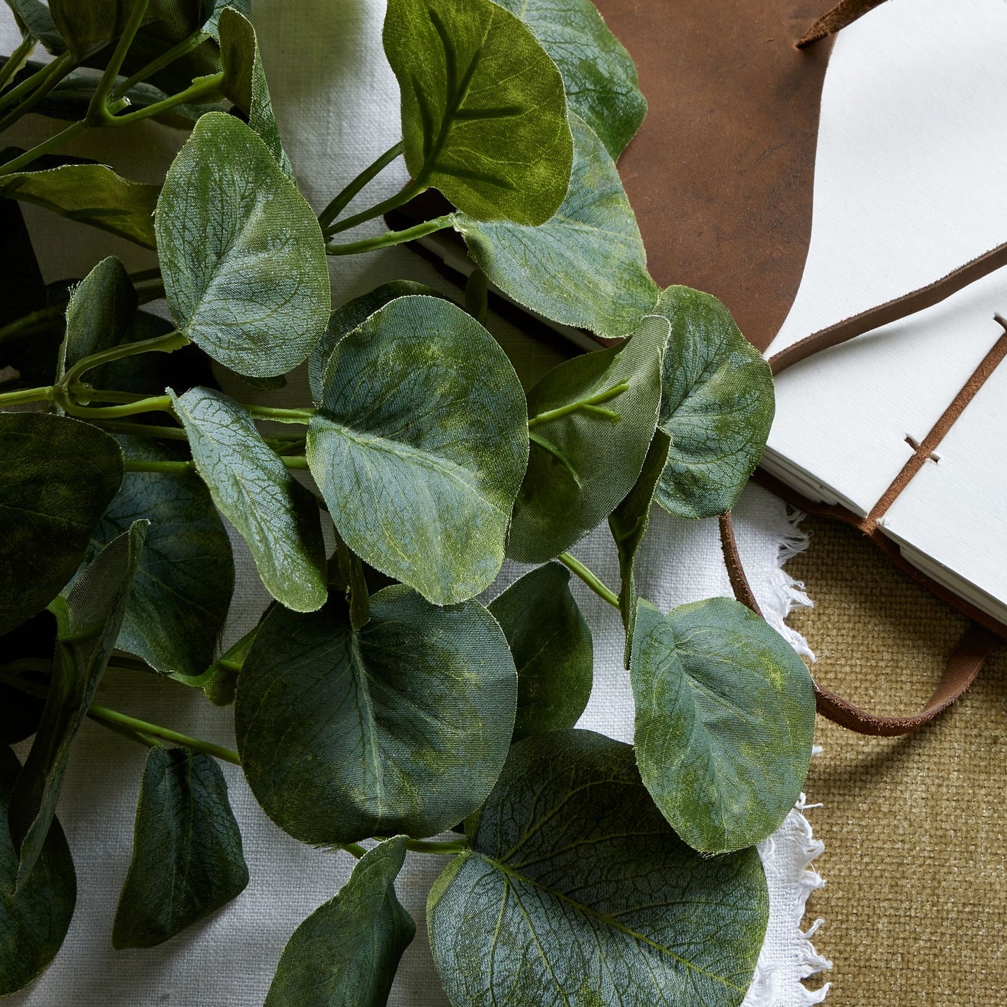 Lush, lifelike green eucalyptus leaves arranged in a compact bunch, perfect for small vases or table displays.