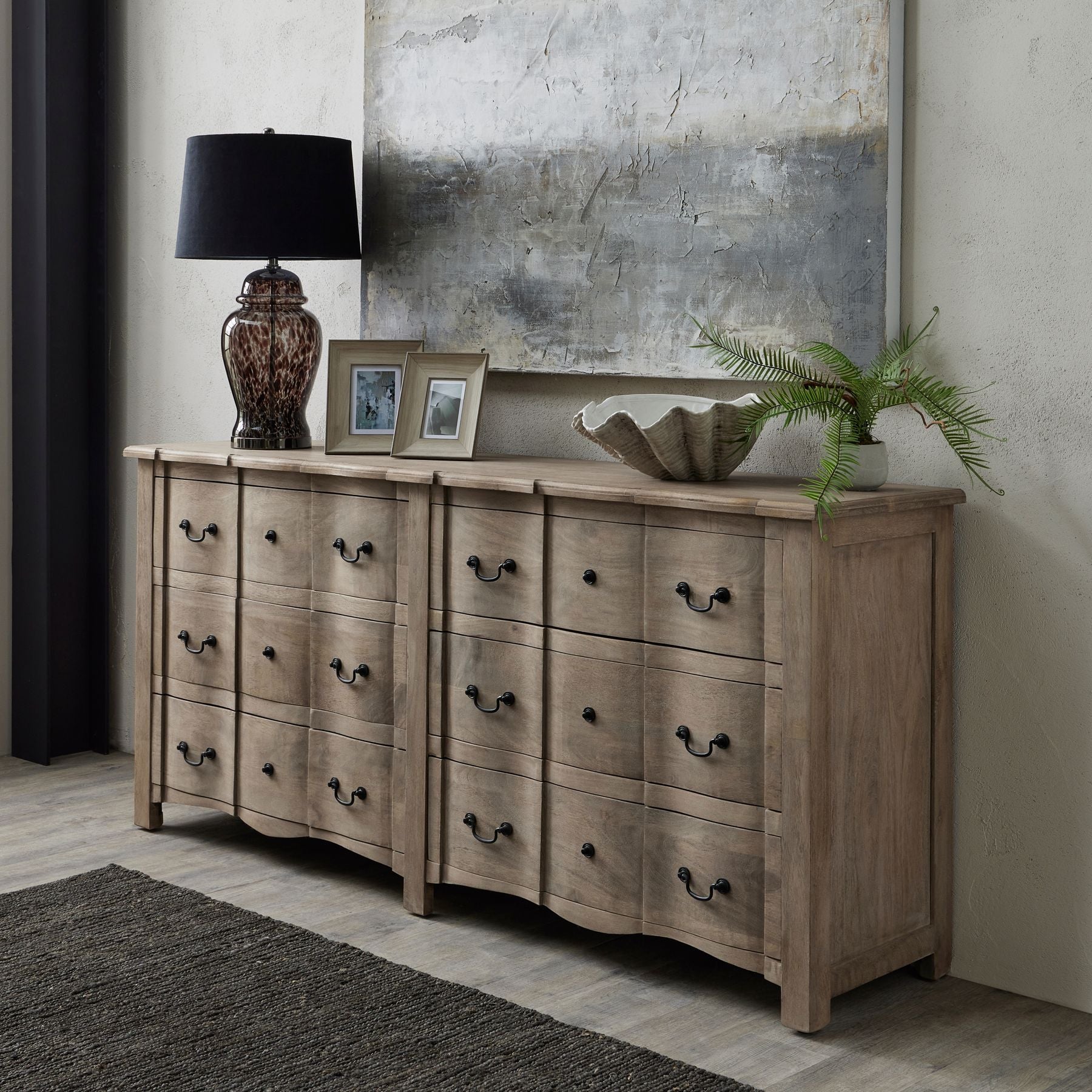 6-drawer chest in washed wood with elegant black iron handles, enhancing a stylish interior alongside a lamp and decor.