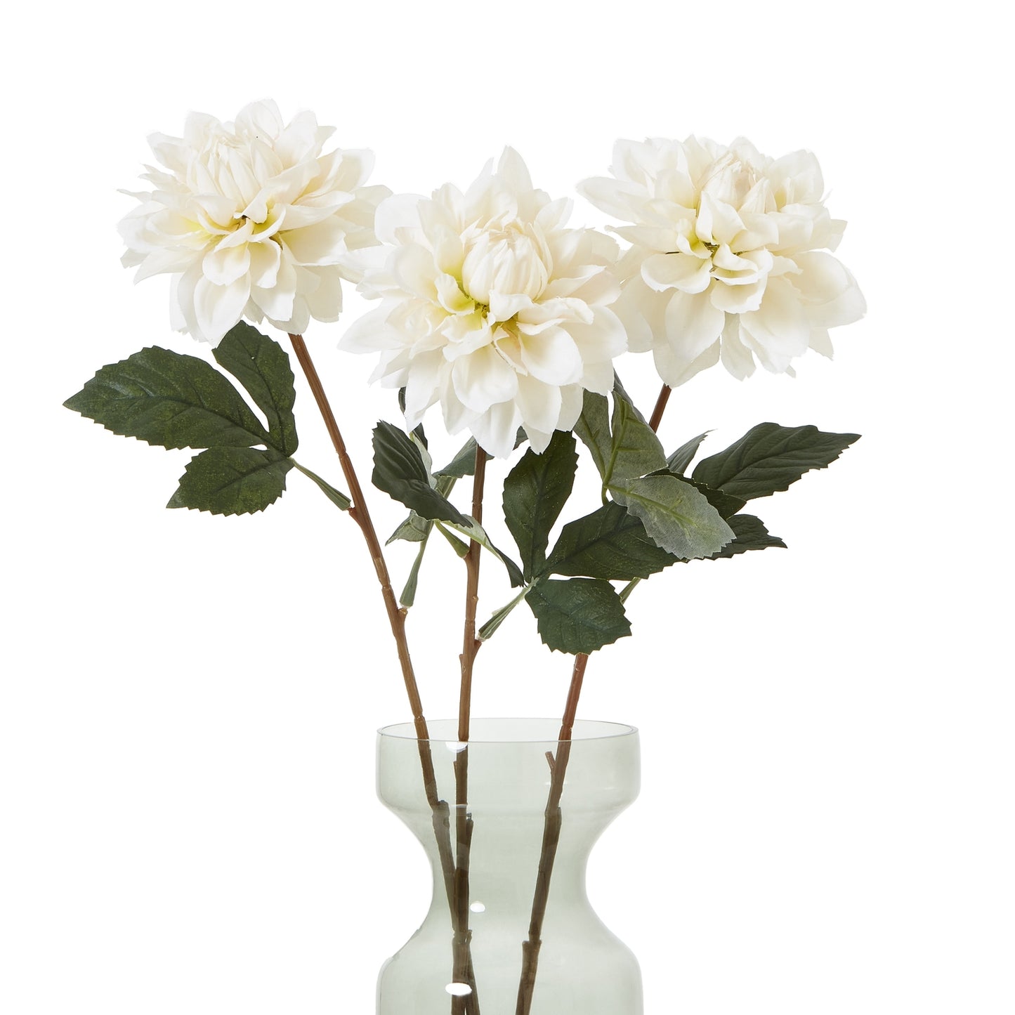 Three tall, white artificial dahlias with layered petals and green leaves in a clear vase, showcasing elegant and timeless floral decor.