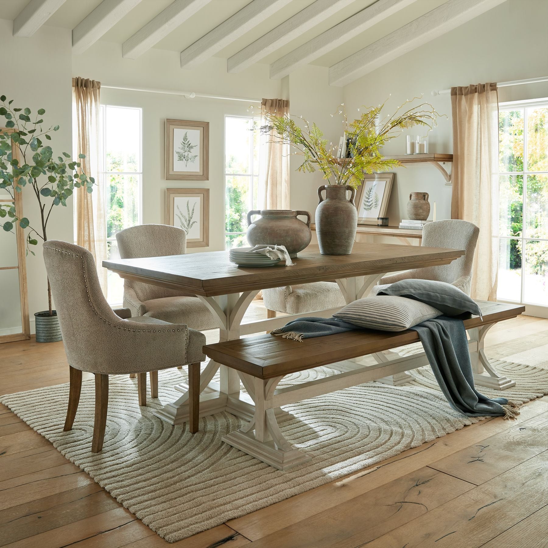 Large green bracken fern spray with intricate frond details, set against a light, airy dining space with natural textures.