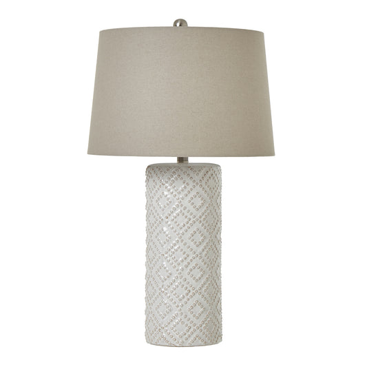 White beaded ceramic lamp with an elegant linen shade, featuring textured craftsmanship and a warm, inviting glow.