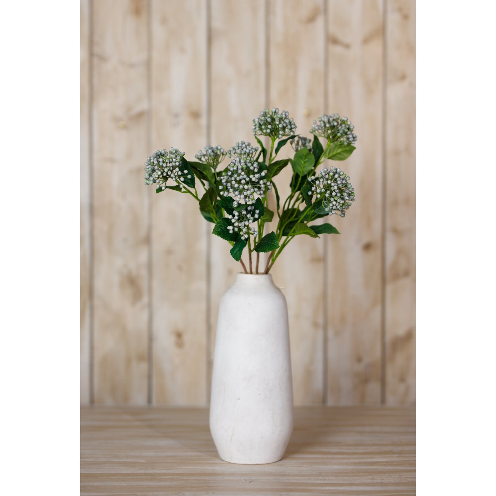 Lifelike blue buds on a single stem, arranged in a white vase against a rustic wooden background, perfect for elegant decor.