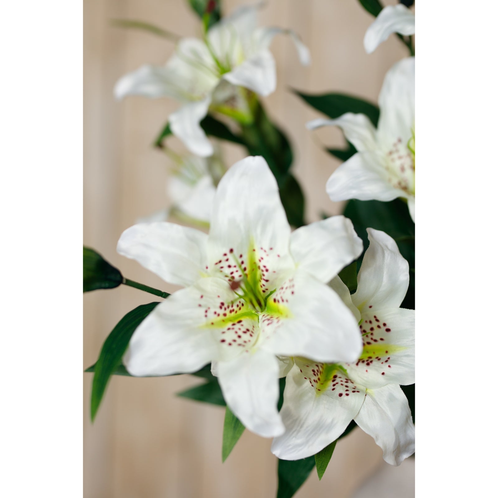 Lifelike white Madonna lily spray featuring delicate blooms with green accents and natural-looking foliage, ideal for elegant decor.
