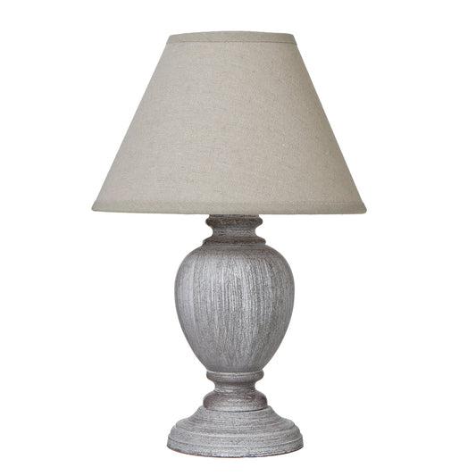 Urn-shaped table lamp with a distressed pewter base and neutral linen shade, creating a warm, inviting light.