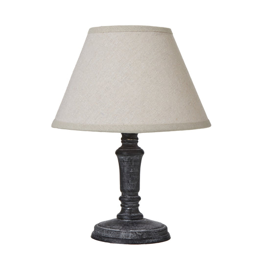 Distressed black base table lamp with a neutral linen shade, offering warm ambiance and versatile style for any decor.