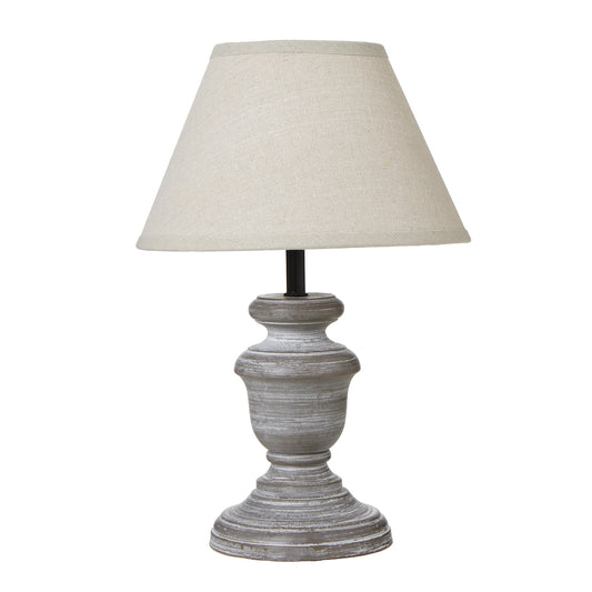 Belluno table lamp with a distressed gray base and a beige linen shade, offering a warm and inviting glow for any space.