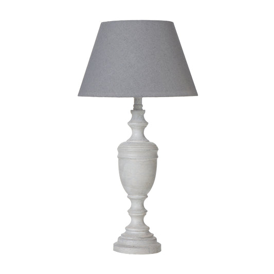 Lentia urn table lamp with a weathered white base and gray linen shade, providing warm illumination for elegant decor.