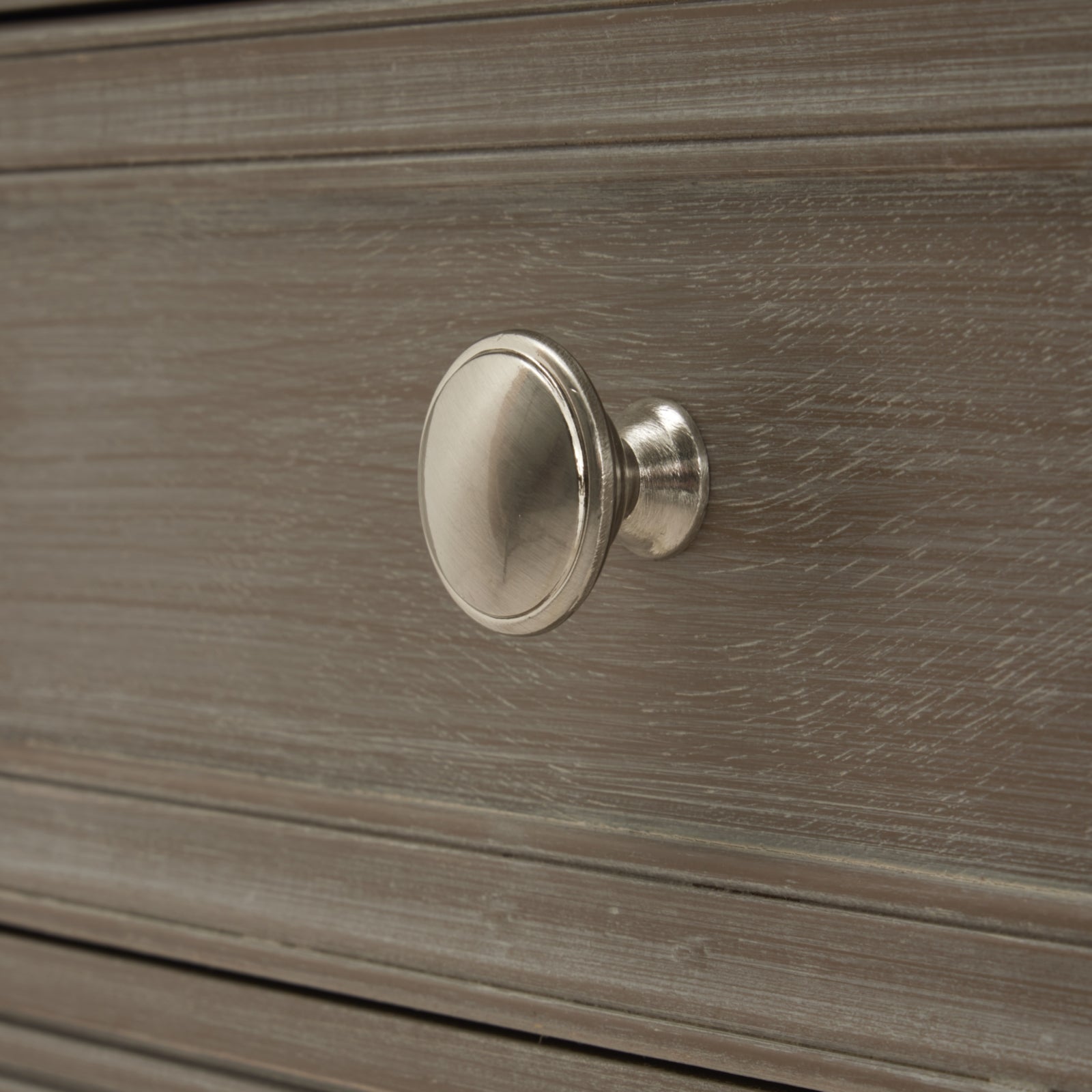 Close-up of a side table drawer in a refined oak finish, featuring a sleek silver knob and subtle wood grain texture.
