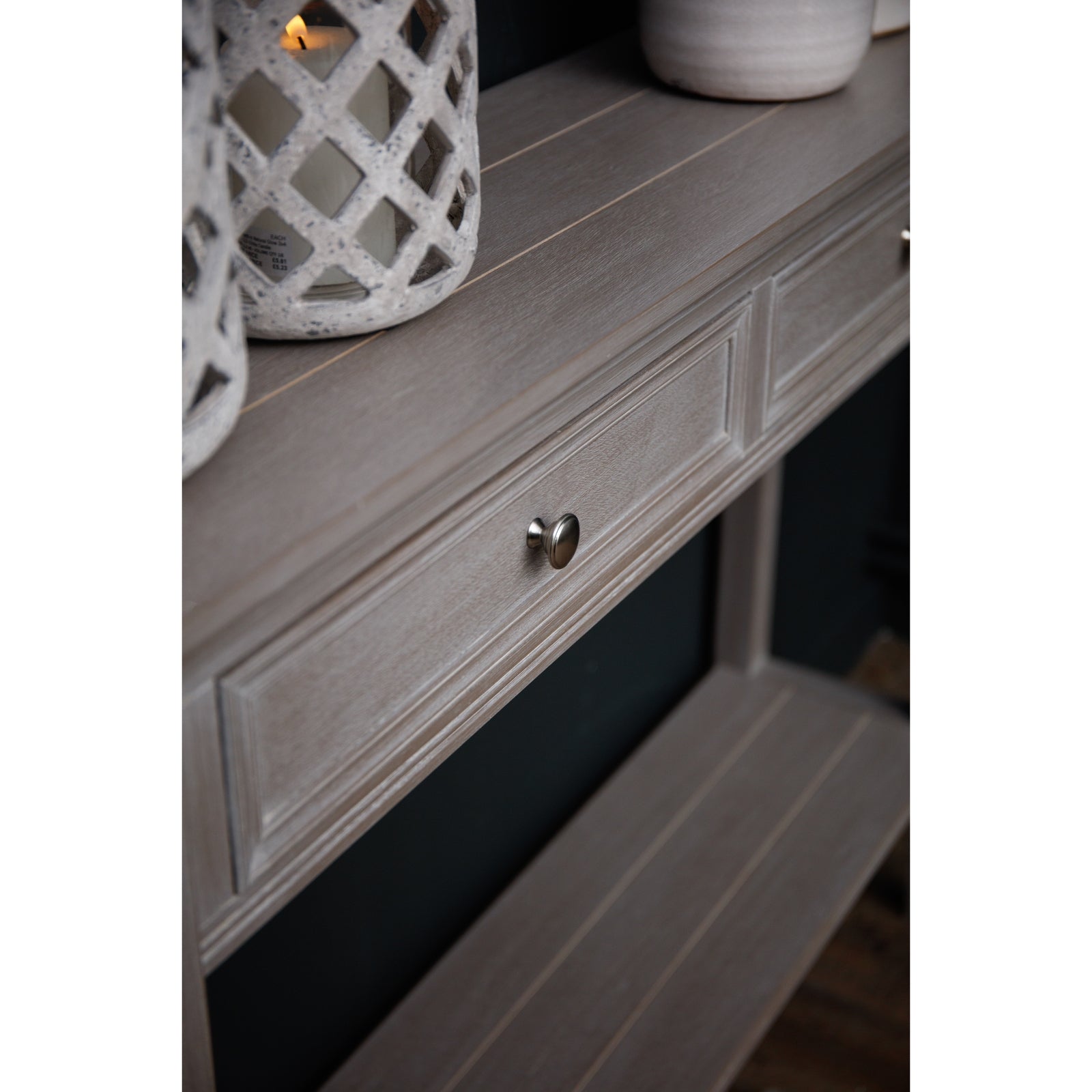 Light gray console table with two drawers, featuring a polished look, subtle detailing, and metallic knobs, set against a dark background.
