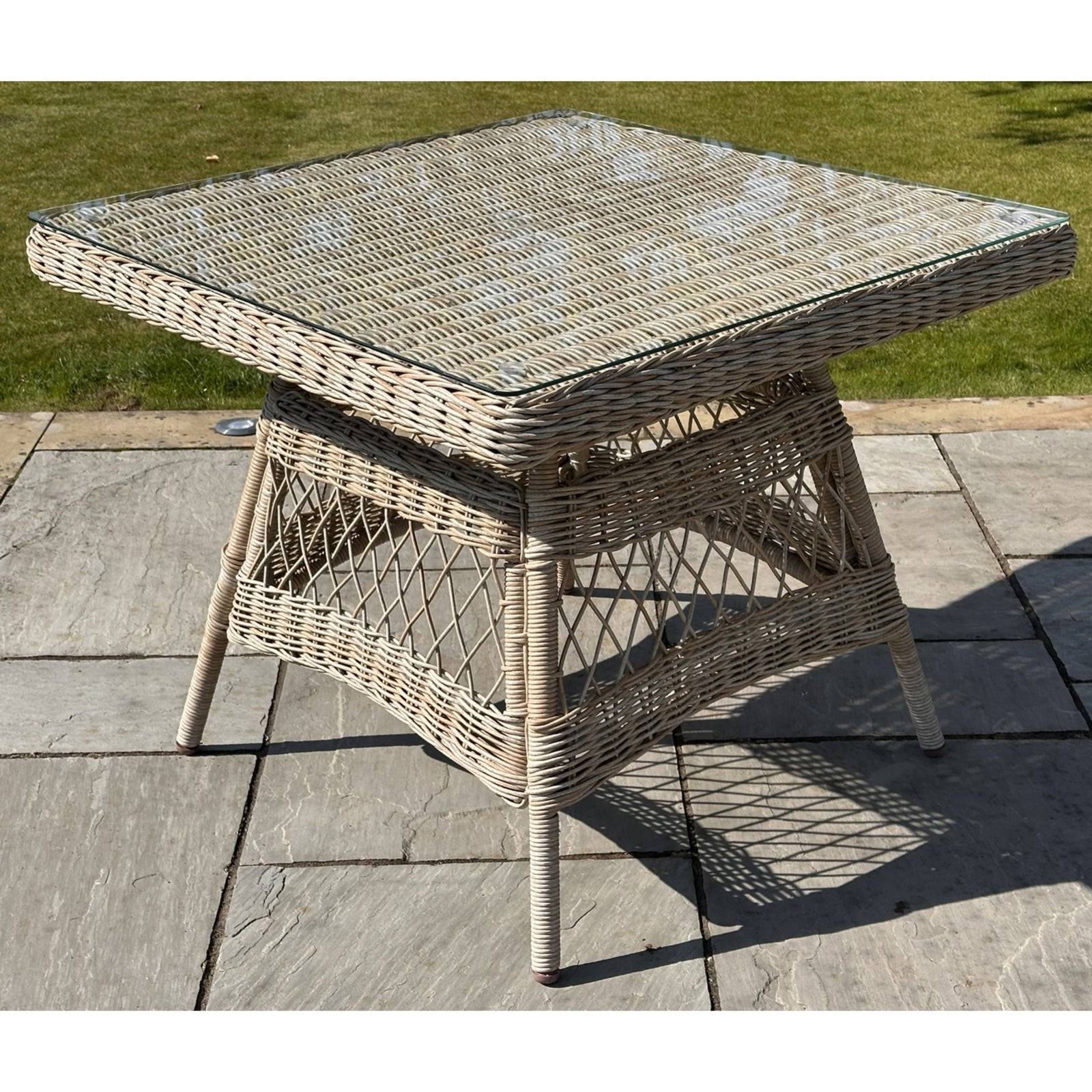 Sophisticated outdoor dining set featuring a weatherproof rattan table with a glass top, complemented by chunky weave design.