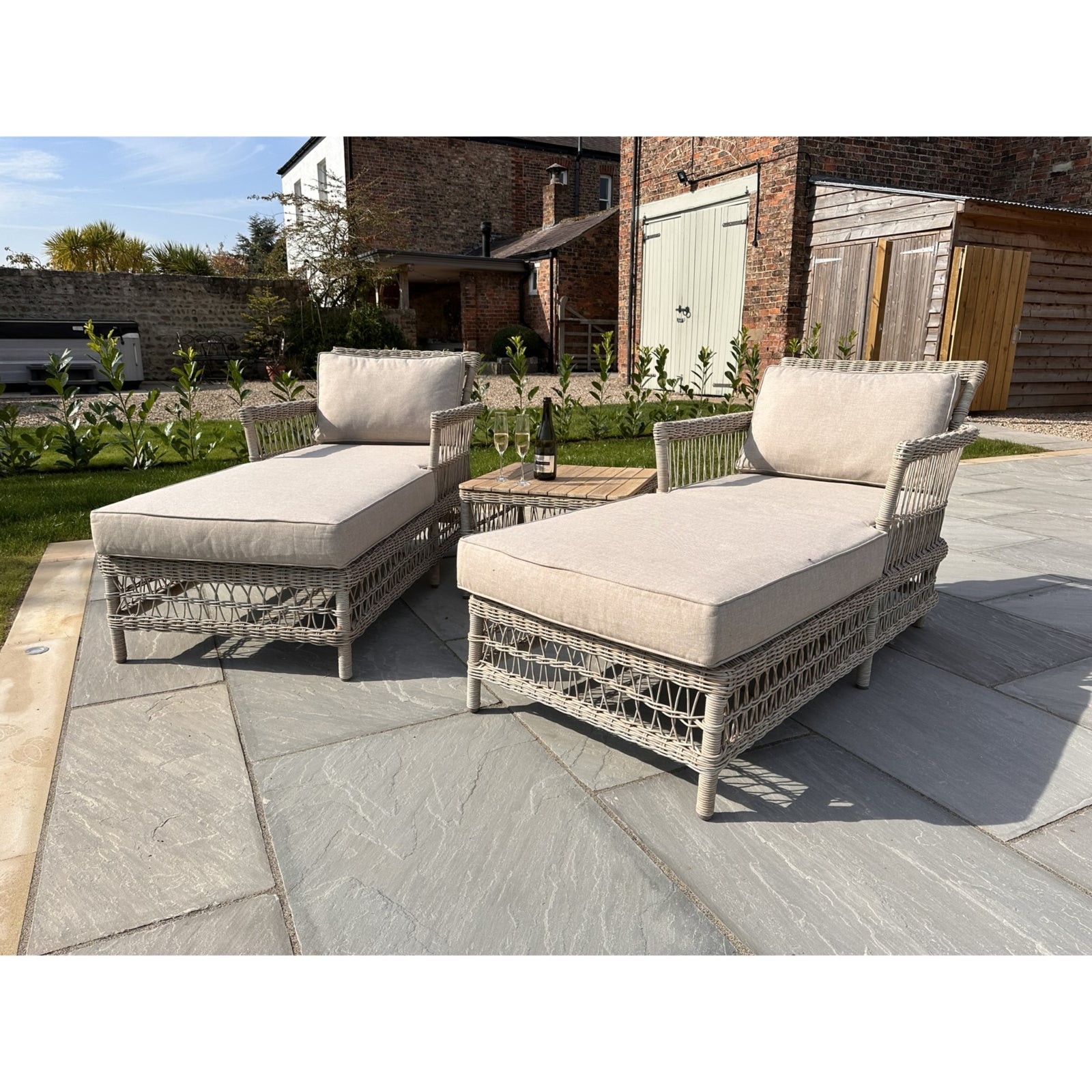 Luxurious outdoor sun lounger set featuring beige cushions and a stylish gray rattan weave, perfect for a sophisticated garden retreat.