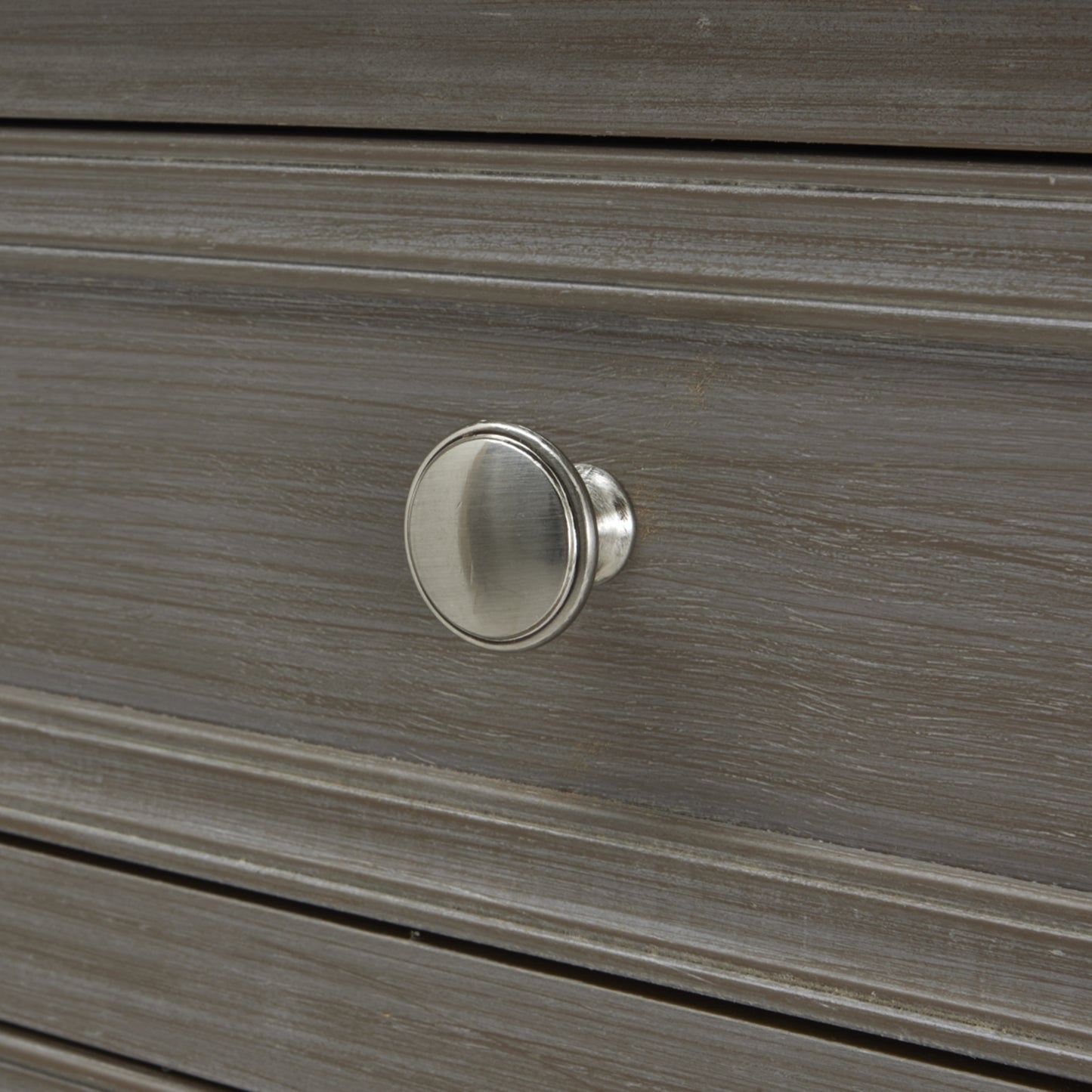 Close-up of a brushed silver knob on a sleek, gray console table with elegant lines and refined craftsmanship.