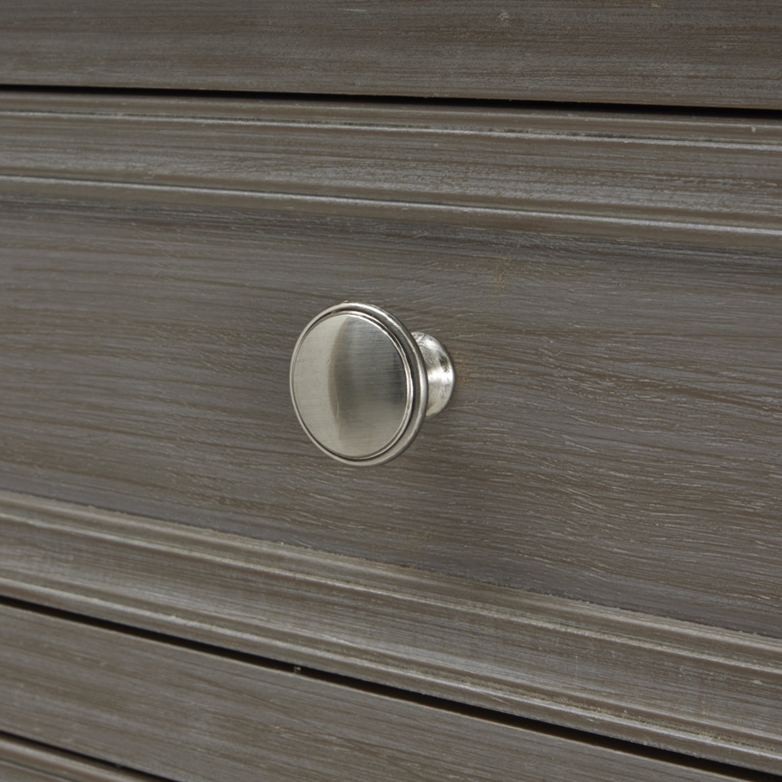 Close-up of a brushed silver knob on a sleek, gray console table with elegant lines and refined craftsmanship.