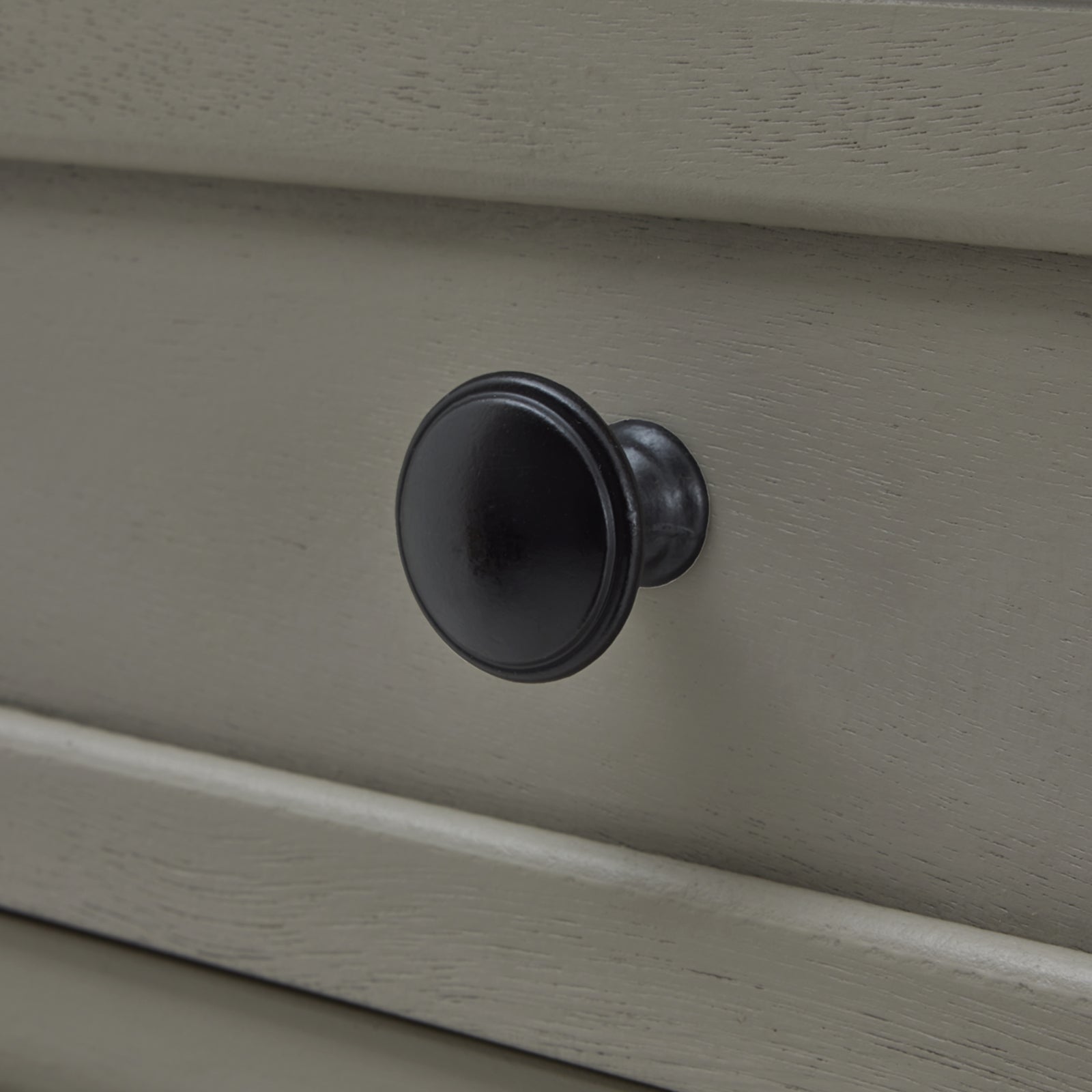 Black drawer knob on a light gray console table showcasing refined craftsmanship and elegant design.