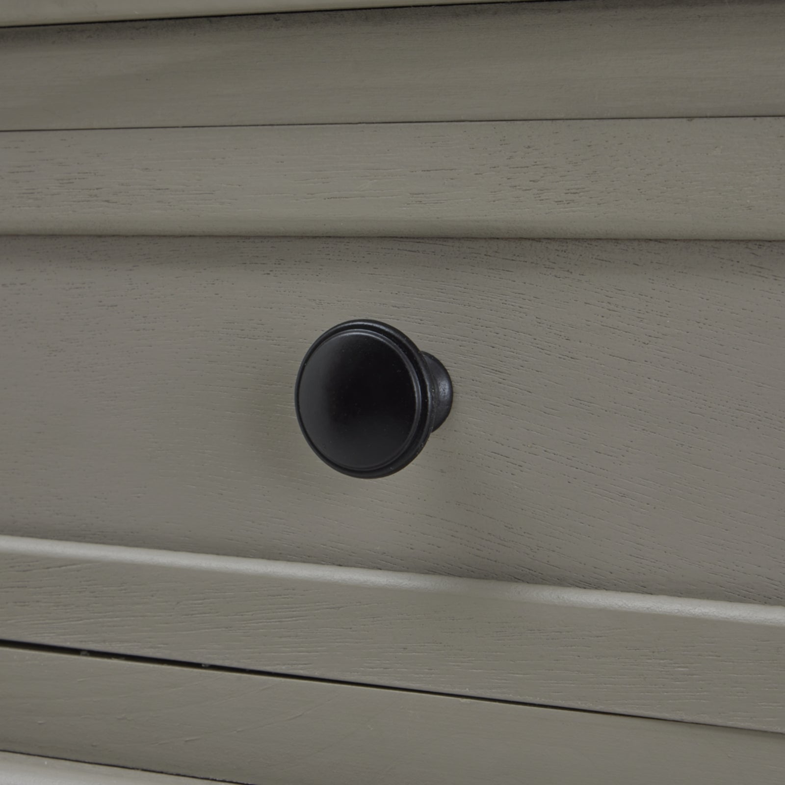 Black round knob on a grey console table drawer, showcasing elegant craftsmanship and modern British design.
