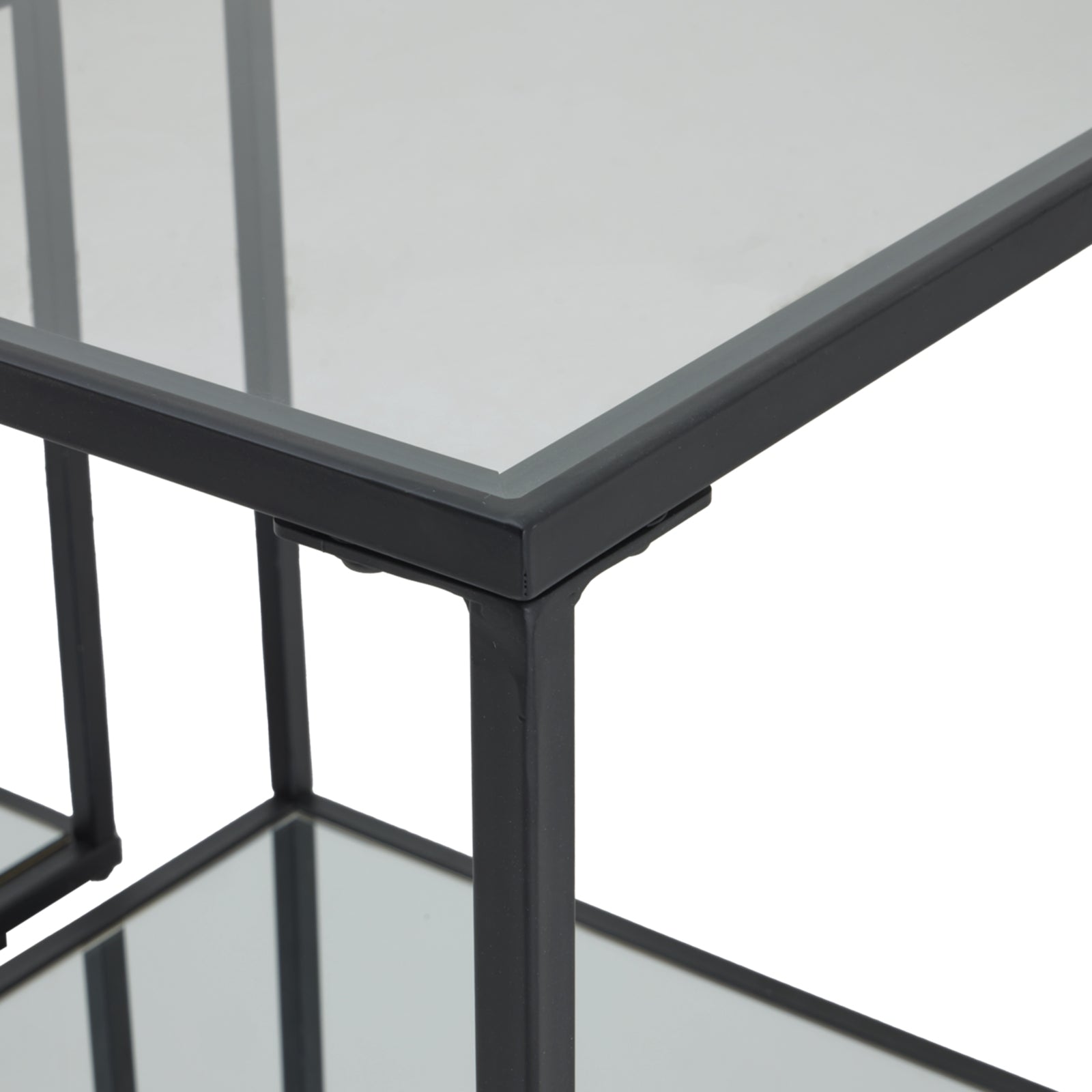 Sleek black framed side tables with glass tops, showcasing a modern design and industrial craftsmanship for versatile use.